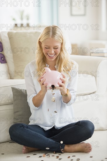 Portrait of young woman empting coins from piggy bank.
Photo : Jamie Grill