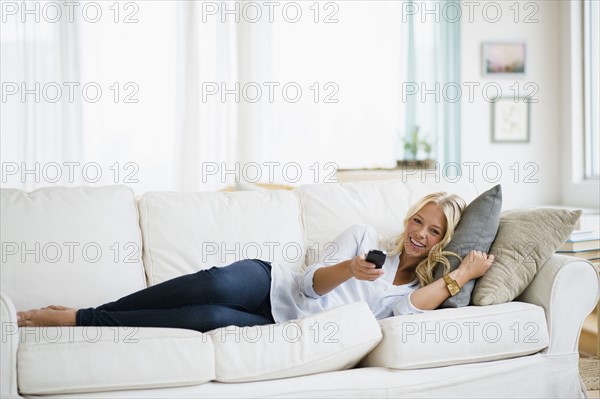 Young woman watching tv on sofa.
Photo : Jamie Grill