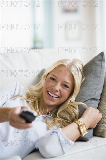 Young woman watching tv on sofa.
Photo : Jamie Grill