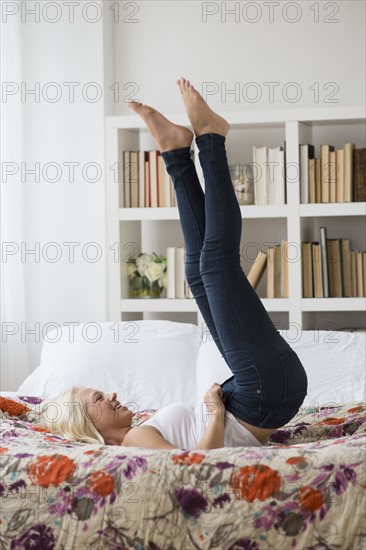 Woman putting on skinny jeans on bed.
Photo : Jamie Grill