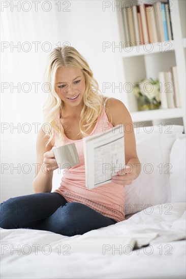 Young woman reading newspaper in bedroom.
Photo : Jamie Grill