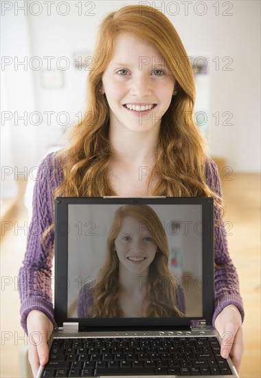 Portrait of girl (12-13) holding laptop.
Photo : Jamie Grill