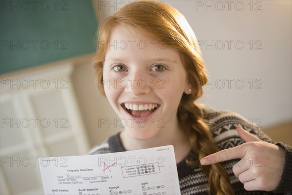 Portrait of girl (12-13) showing exam sheet.
Photo : Jamie Grill