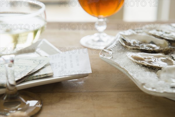 Studio shot of oysters, champagne and bill.
Photo : Jamie Grill