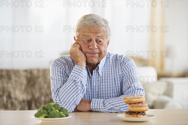 Portrait of senior man looking at doughnut.
Photo : Jamie Grill