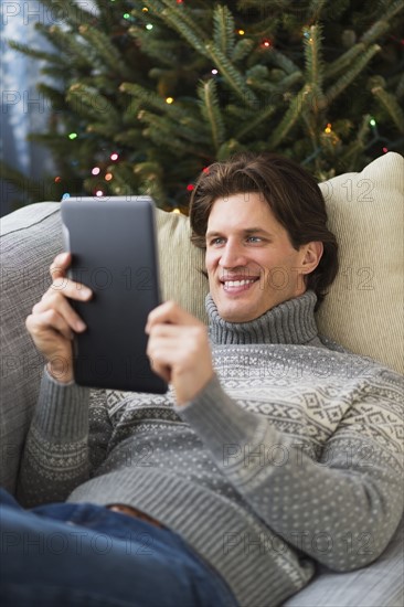 Man lying on sofa and using tablet.
Photo : Daniel Grill