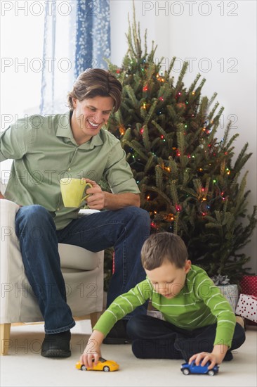 Man drinking tea and boy (6-7) playing with cars.
Photo : Daniel Grill