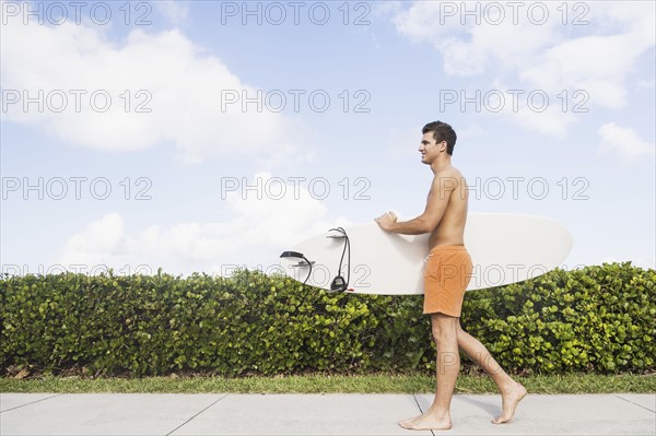 Young man carrying surfboard. Jupiter, Florida, USA.
Photo : Daniel Grill