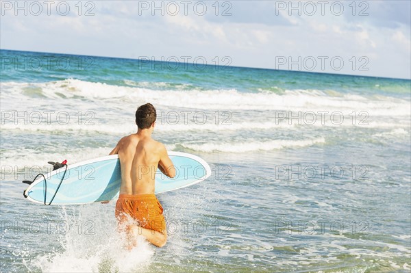 Young man carrying surfboard. Jupiter, Florida, USA.
Photo : Daniel Grill