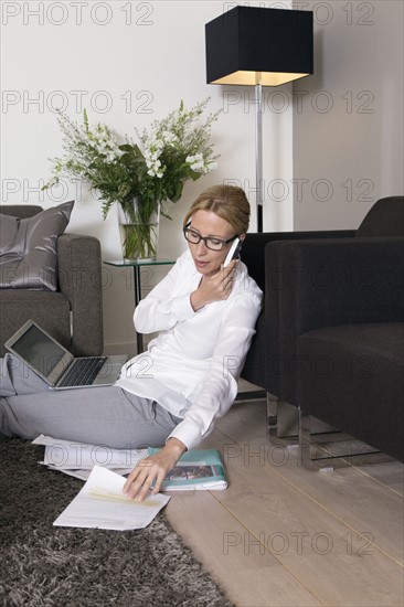 Woman sitting on floor and talking on mobile.
Photo : Mark de Leeuw