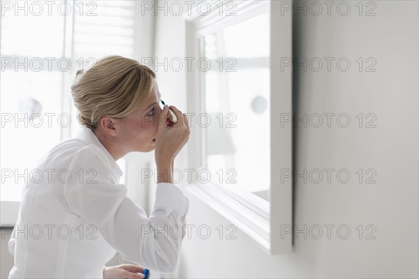 Woman applying make-up.
Photo : Mark de Leeuw