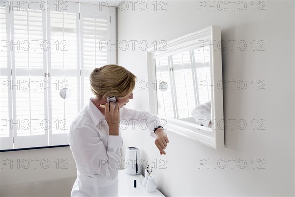 Woman checking time and talking on mobile.
Photo : Mark de Leeuw