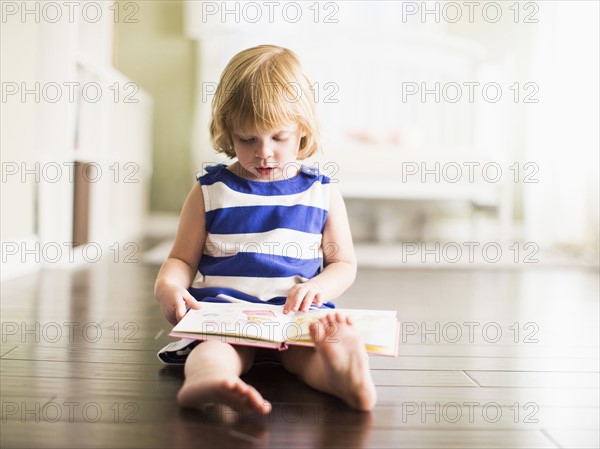 Girl (4-5) reading book.
Photo : Jessica Peterson