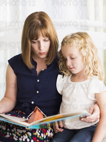 Mother reading book with daughter (6-7).
Photo : Jessica Peterson