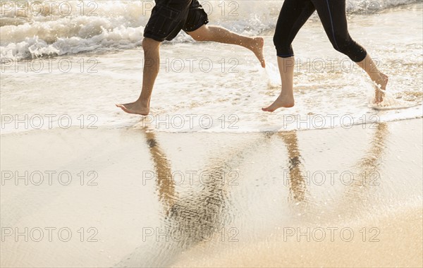 Couple running on beach, low section.