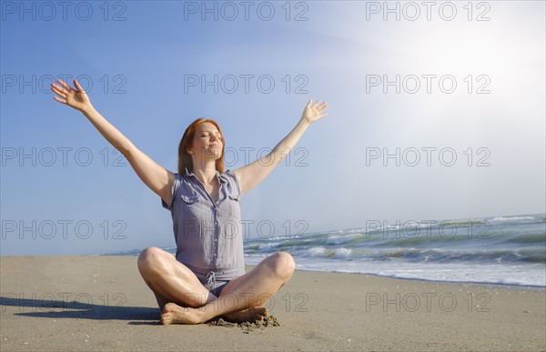 Woman practicing yoga on beach.