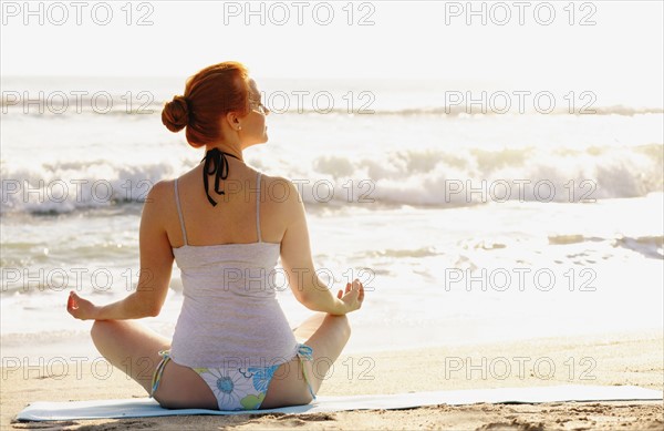 Woman practicing yoga on beach.