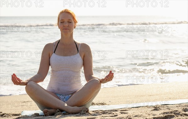 Woman practicing yoga on beach.