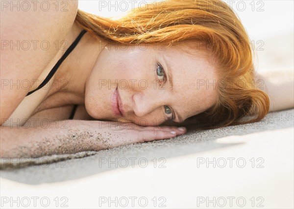 Portrait of woman lying on beach.