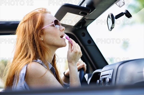 Woman doing make up in car.