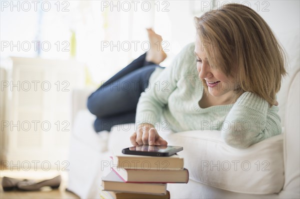 Woman lying on sofa and using digital tablet.