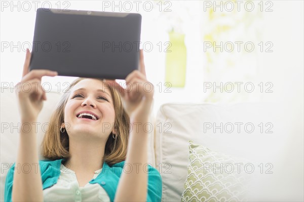 Portrait of woman on sofa using digital tablet.