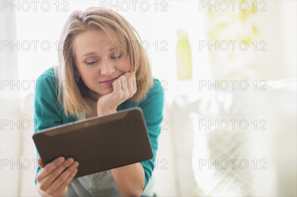 Portrait of woman on sofa using digital tablet.