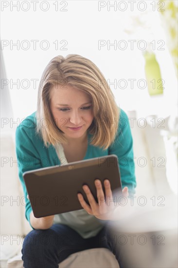 Portrait of woman on sofa using digital tablet.