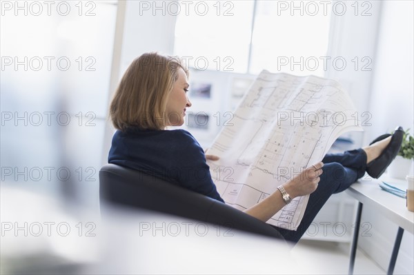 Business woman looking at blueprint in office.
