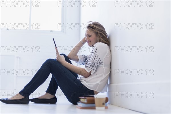 Young woman sitting on floor and using digital tablet.