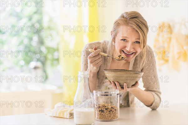 Young woman eating granola for breakfast.