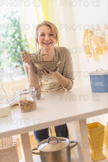 Young woman eating granola for breakfast.