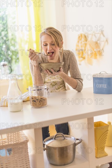 Young woman eating granola for breakfast.