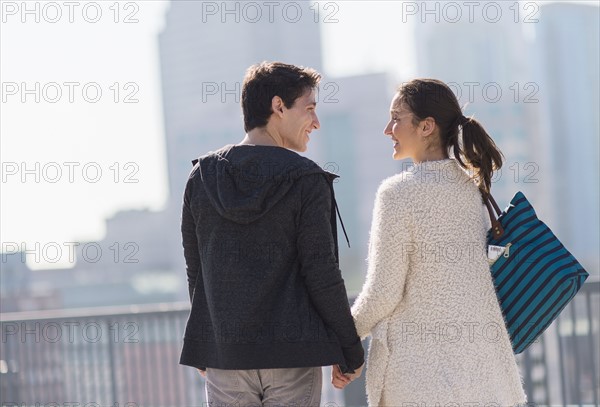 Young couple walking, buildings in background.