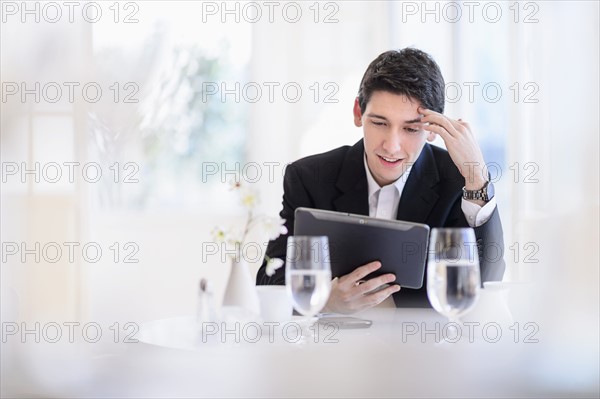 Portrait of business man using digital tablet in restaurant.