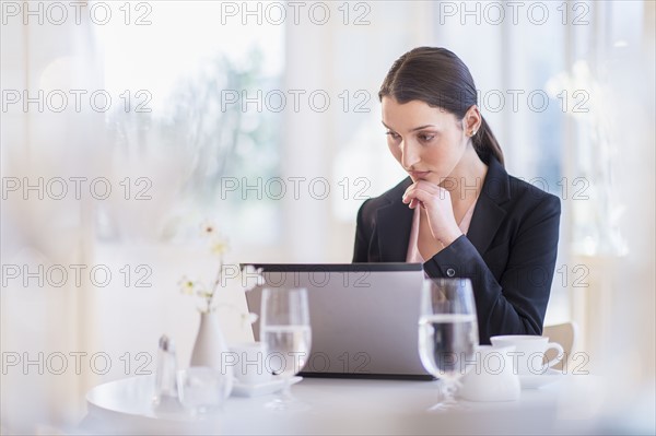 Businesswoman working on laptop in restaurant.