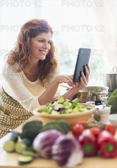 Woman cooking and using digital tablet in kitchen.