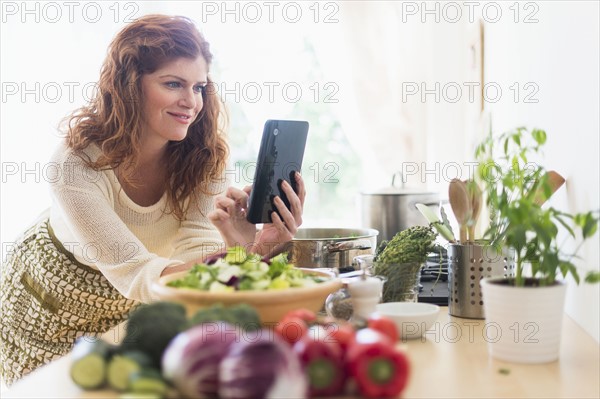 Woman cooking and using digital tablet in kitchen.