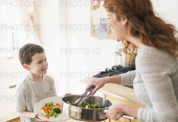 Mother and son (6-7) serving healthy dinner.