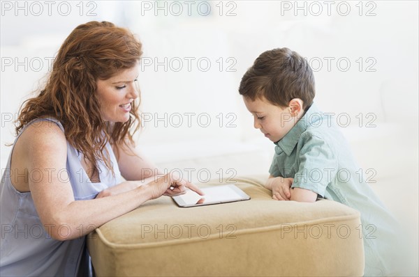 Mother and son (6-7) using digital tablet.
