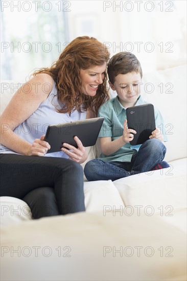 Mother and son (6-7) using digital tablets.