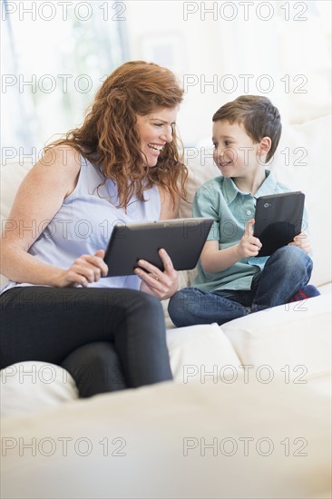 Mother and son (6-7) using digital tablets.