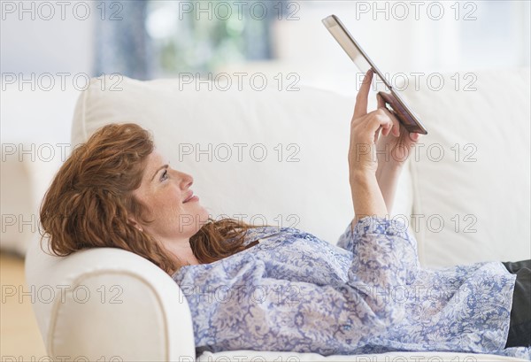 Woman lying on sofa and using laptop.