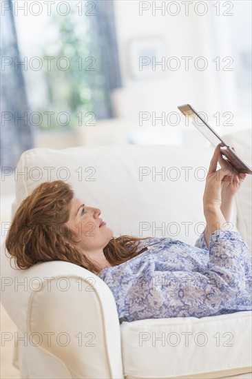 Woman lying on sofa and using laptop.