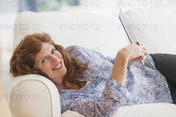 Woman lying on sofa and using laptop.