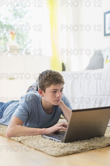 Teenage boy (16-17) using laptop.