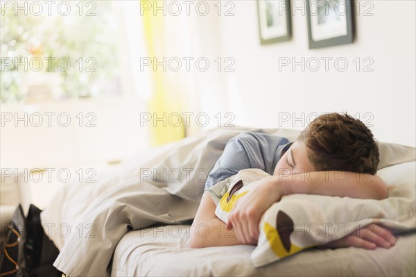 Teenage boy (16-17) sleeping in bed.