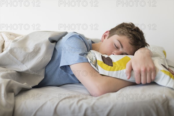 Teenage boy (16-17) sleeping in bed.