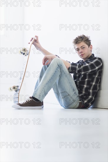 Teenage boy (16-17) holding skateboard.