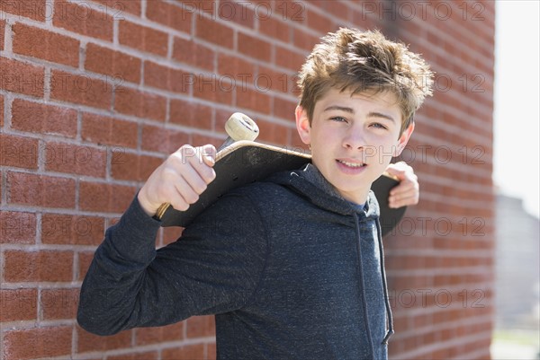 Teenage boy (16-17) holding skateboard.